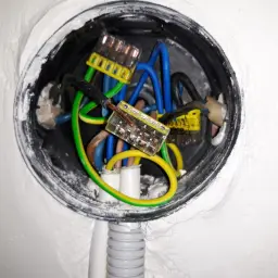 Widać instalację elektryczną z przewodami w puszkach, sugerującą niskie napięcie w gniazdku.