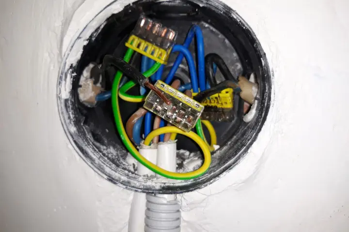 Widać instalację elektryczną z przewodami w puszkach, sugerującą niskie napięcie w gniazdku.